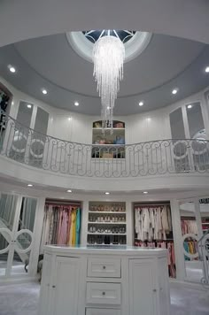 the inside of a closet with chandelier hanging from it's ceiling and lots of clothes on shelves