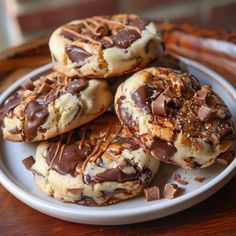 three chocolate covered cookies on a plate with some drizzled in the middle