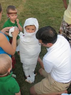 a group of people in costumes standing around each other on the grass with one child dressed up as an egret