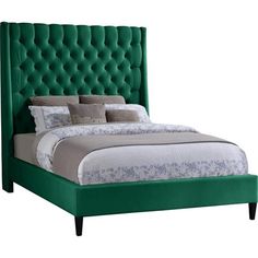 a bed with green upholstered headboard and pillows