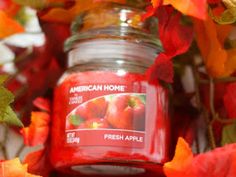 an american home candle surrounded by autumn leaves