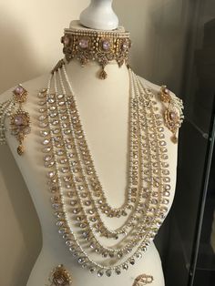 a white mannequin with several necklaces and earrings on it's chest