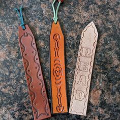 three leather bookmarks sitting on top of a granite counter