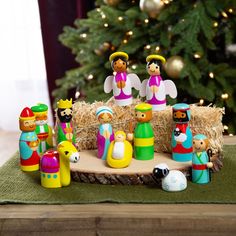 a group of wooden toy figurines sitting next to a christmas tree