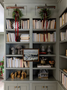 a bookshelf filled with lots of books next to a christmas tree and other decorations