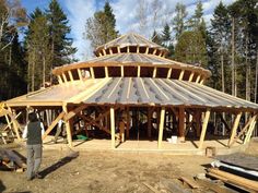 a man standing in front of a wooden structure with wood framing on the roof and sides