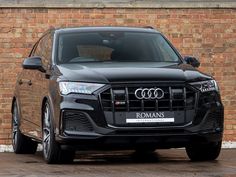 an audi suv parked in front of a brick wall with the name romans on it