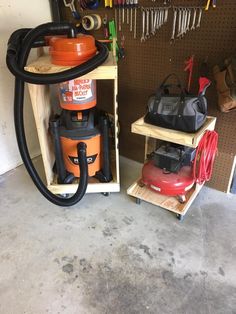 a couple of different types of vacuums in a storage area with tools hanging on the wall