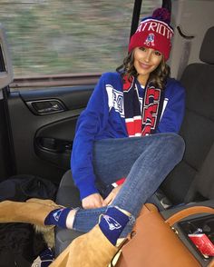 a woman sitting in the back seat of a car with her feet propped up on luggage