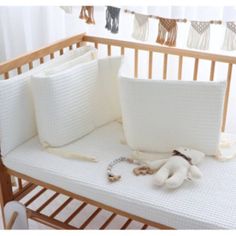 a crib with white pillows and accessories on it