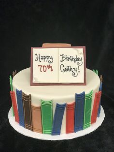 a birthday cake decorated with books and the words happy 70th birthday written on it