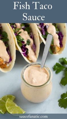 three tacos with sauce and garnish on a table next to lime wedges