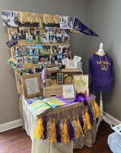 a table with purple and yellow decorations on it in front of a wall full of pictures