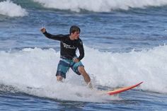 a man riding a surfboard on top of a wave in the ocean with waves behind him