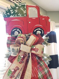 a red truck is decorated with burlocks and ribbon for the christmas tree on display