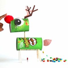 a hand is holding a candy bar with reindeer antlers on it and some candies scattered around