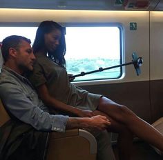 a man and woman sitting on a train looking out the window