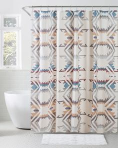 a shower curtain with an abstract design in the middle and a white bathtub next to it