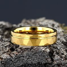 a gold wedding ring sitting on top of a rock