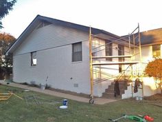 a white house with stairs and ladders in the front yard