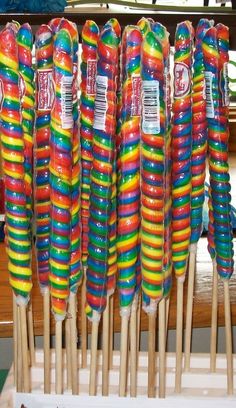 many colorful lollipops are lined up on sticks