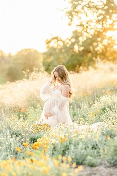 a pregnant woman standing in a field of flowers