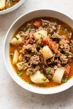 two bowls of soup with meat, potatoes and carrots