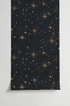 a black background with gold stars in the night sky, and white wall paper behind it