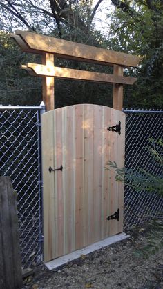 an open wooden gate in front of a chain link fence