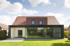 a modern house with large glass windows and brick roof