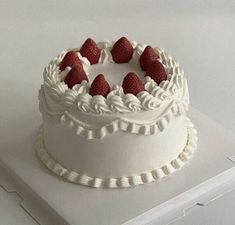 a white cake topped with strawberries on top of a table next to a box