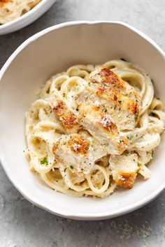 two white bowls filled with pasta and chicken