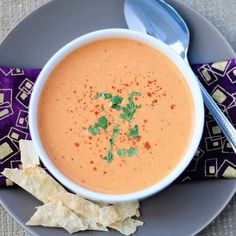 a bowl of soup on a plate with tortilla chips