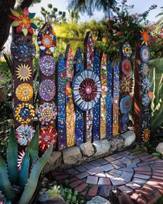 a colorful garden fence made out of stained glass and stone with flowers painted on it