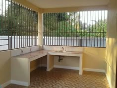 an empty room with two sinks and bars on the windows