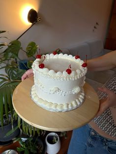 a woman holding a cake with cherries on it