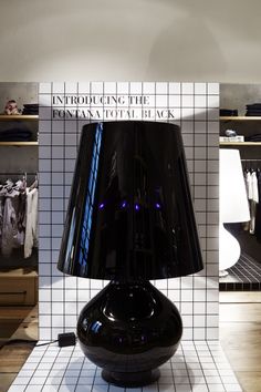 a large black lamp sitting on top of a white tiled floor next to a wall