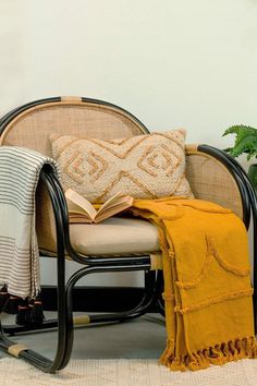 a chair with a book on it next to a potted plant and a blanket