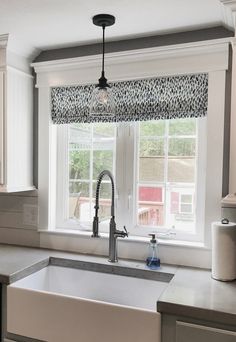 a kitchen sink under a window in front of a counter with a faucet