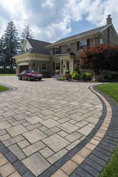 a car is parked in front of a large brick driveway with a stone walkway leading up to it