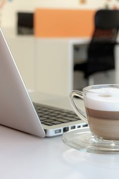 a cup of coffee sitting next to a laptop computer