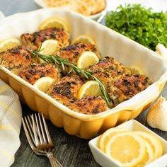 a casserole dish with lemons, herbs and garlic in it on a table