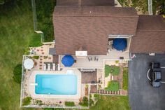 an aerial view of a house with a swimming pool in the yard and two cars parked on the driveway