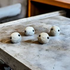 three stone balls with eyes sitting on top of a table