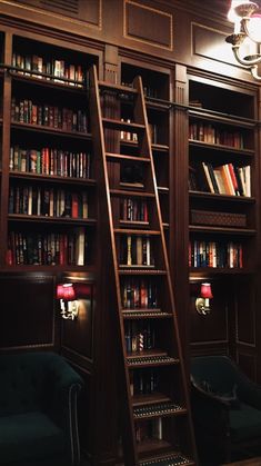 two green chairs in front of a bookshelf with many books on the shelves