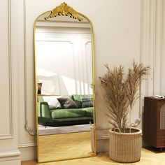 a living room with a green couch and a large gold framed mirror on the wall