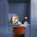 an orange chair sitting in front of a desk with a lamp on top of it