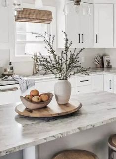 a white kitchen with marble counter tops and wooden stools