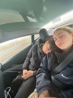 two people sleeping in the back seat of a car on a sunny day with their eyes closed