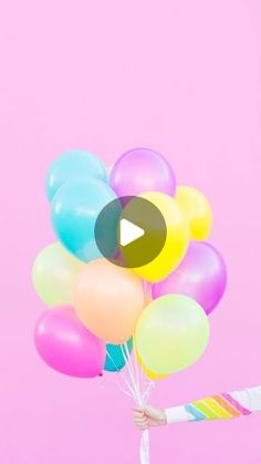 a person holding balloons with a pink background